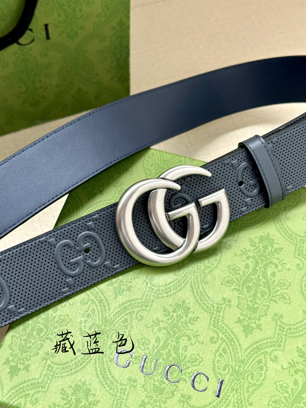 Navy Gucci belt close-up of silver double G buckle and embossed GG monogram strap