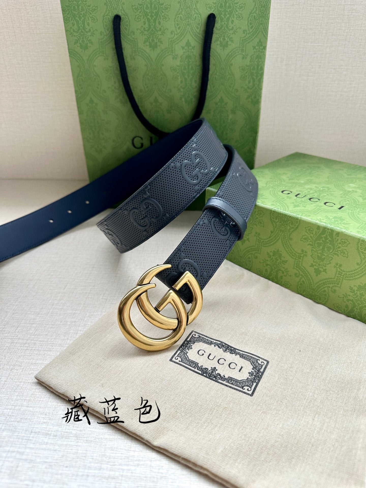 Gucci belt angled view, dark blue strap with embossed GG and gold-tone buckle