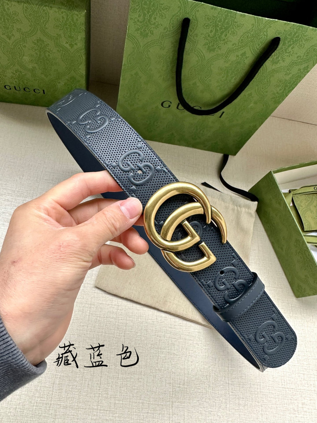 Gucci belt with dark blue strap, perforated GG logo texture and gold-tone buckle