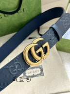 Gucci belt close-up: dark blue perforated GG strap with round gold-tone GG buckle