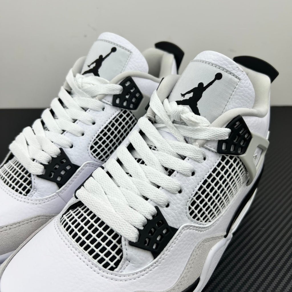Pair of white Air Jordan 4 sneakers with black Jumpman logos and mesh side panels