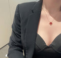 Gold clover pendant necklace worn at the neckline with dark top