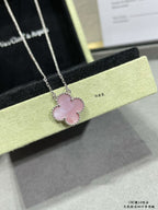 Silver-tone clover pendant necklace with pink center stone and small border stones.
