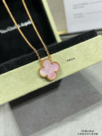 Gold-tone clover pendant necklace with light pink center and scalloped frame.