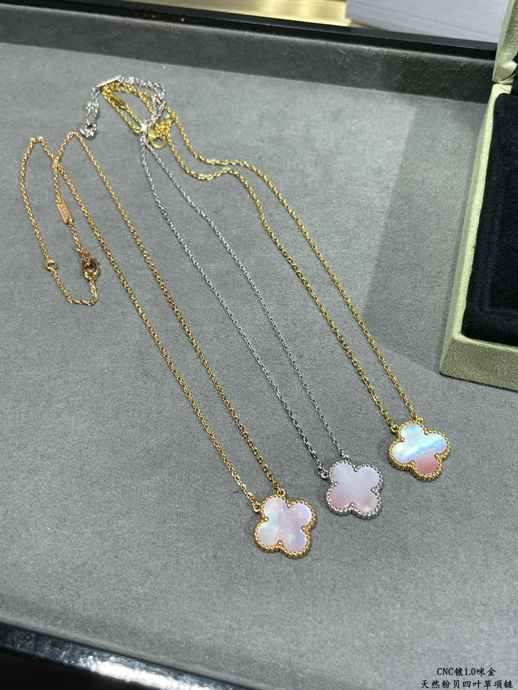 Multi-necklace display with clover pendants in gold and silver tones.