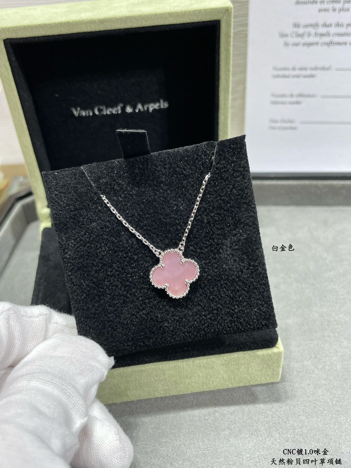 Silver-tone necklace with pink clover pendant on a black jewelry box cushion.