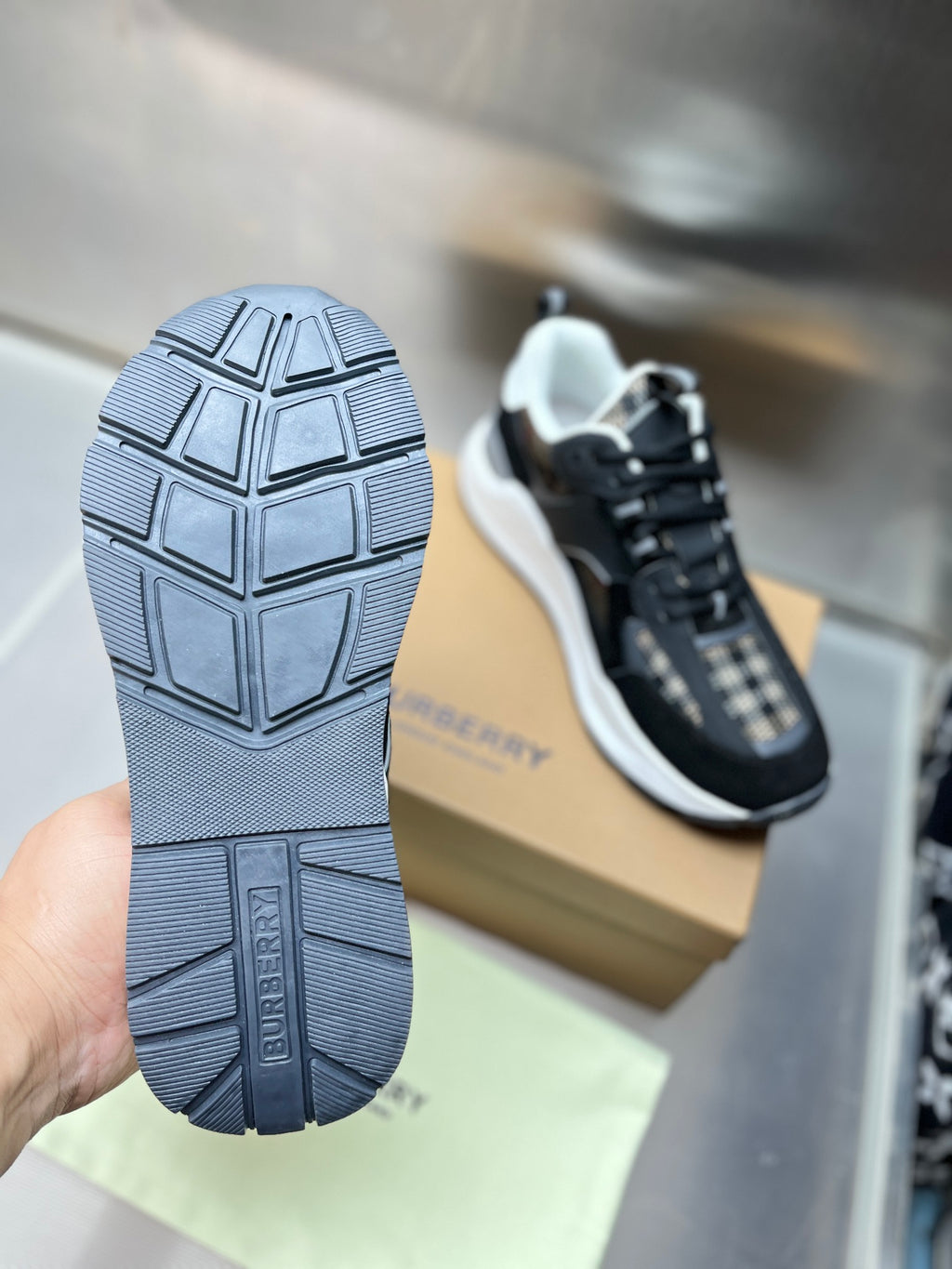 Sneaker outsole with tread and Burberry text, black rubber bottom