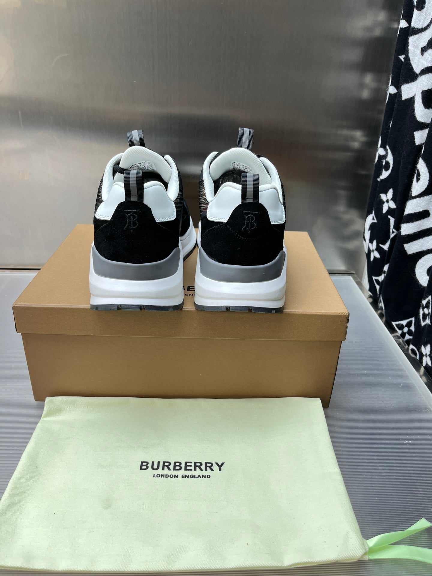 Black sneakers with white midsoles and rear logo accents, lace-up