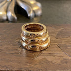 Gold-colored ring with engraved floral accents and a glossy, reflective band.