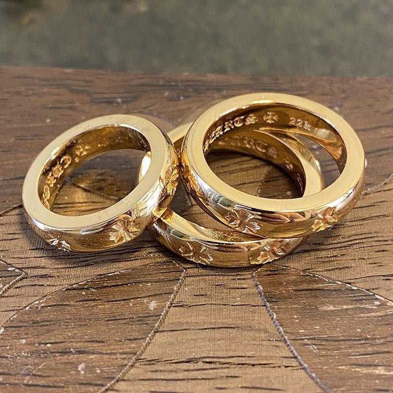 Two gold-colored rings stacked, both with engraved floral pattern on the band.