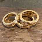 Two gold-colored rings stacked, both with engraved floral pattern on the band.