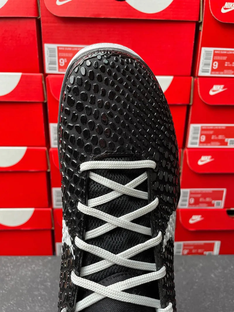 Black Nike basketball shoe toe view with white laces and textured traction upper