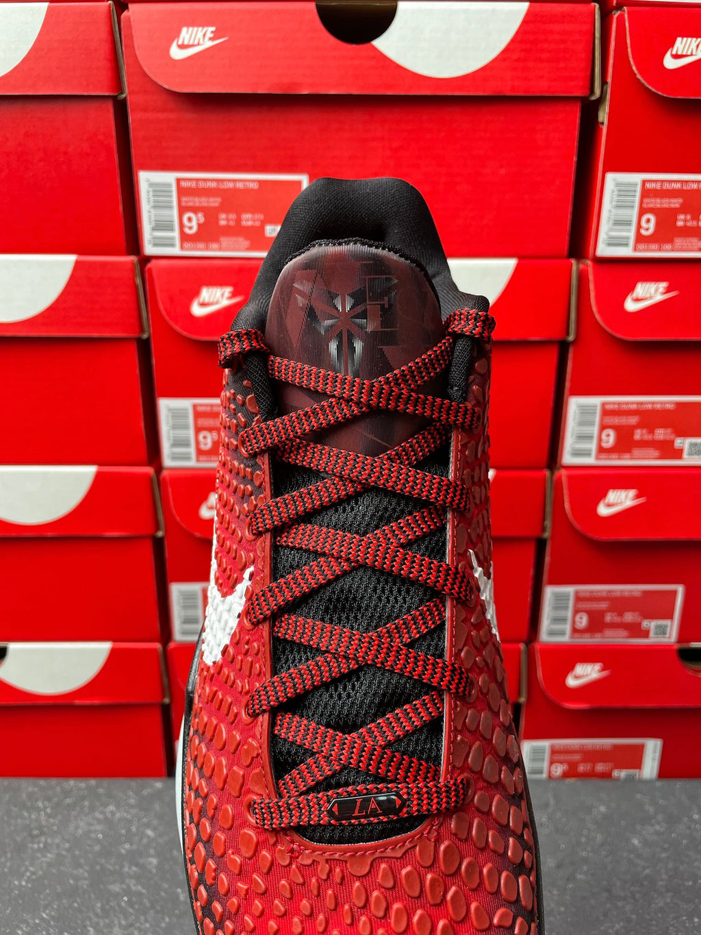 Red athletic shoe back view with black laces and black heel tab