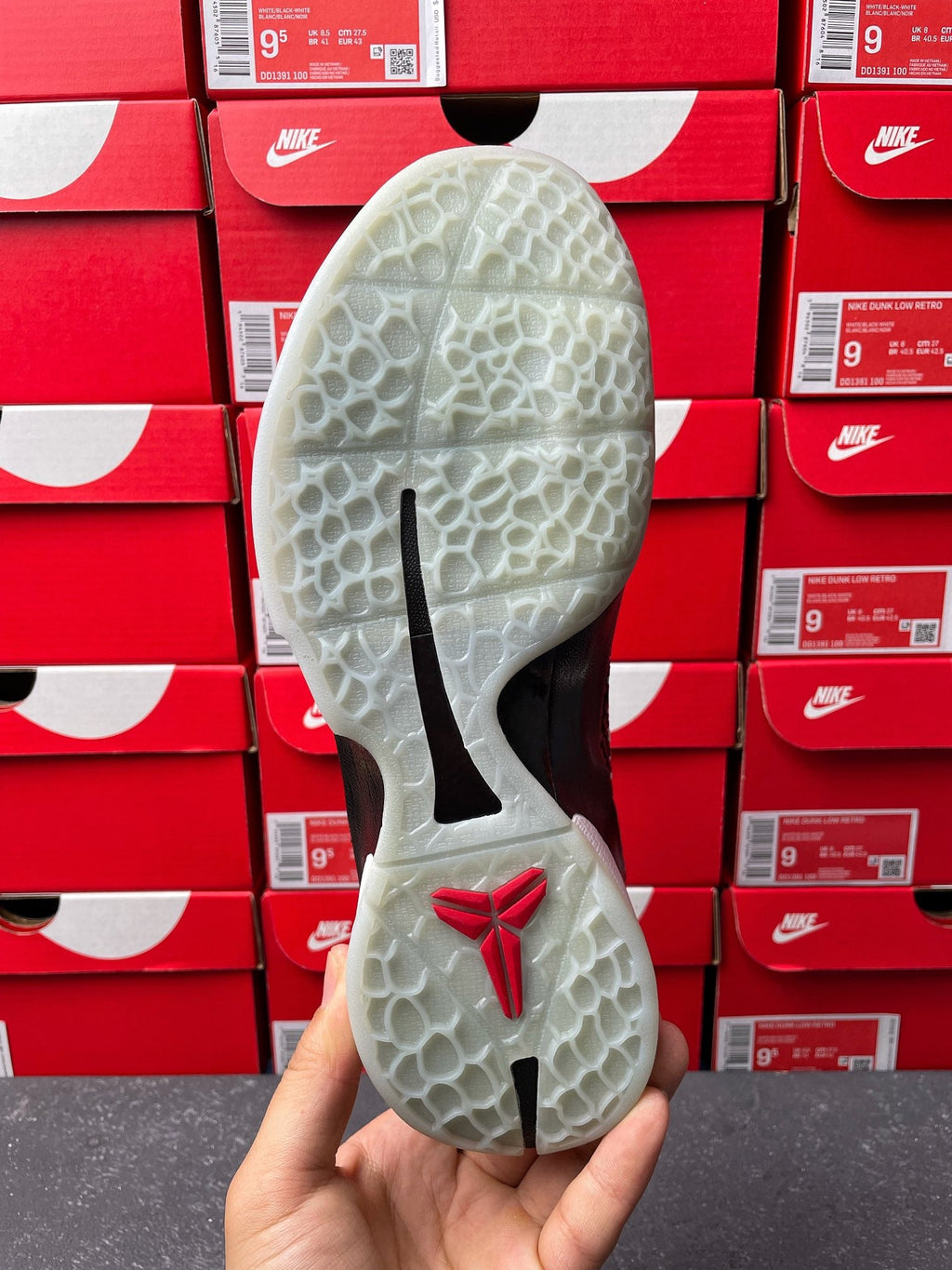 Athletic shoe outsole with light tread pattern, black stripes, and red logo