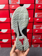 Athletic shoe outsole with light tread pattern, black stripes, and red logo