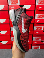 Red textured athletic shoe side view with white swoosh and black midsole