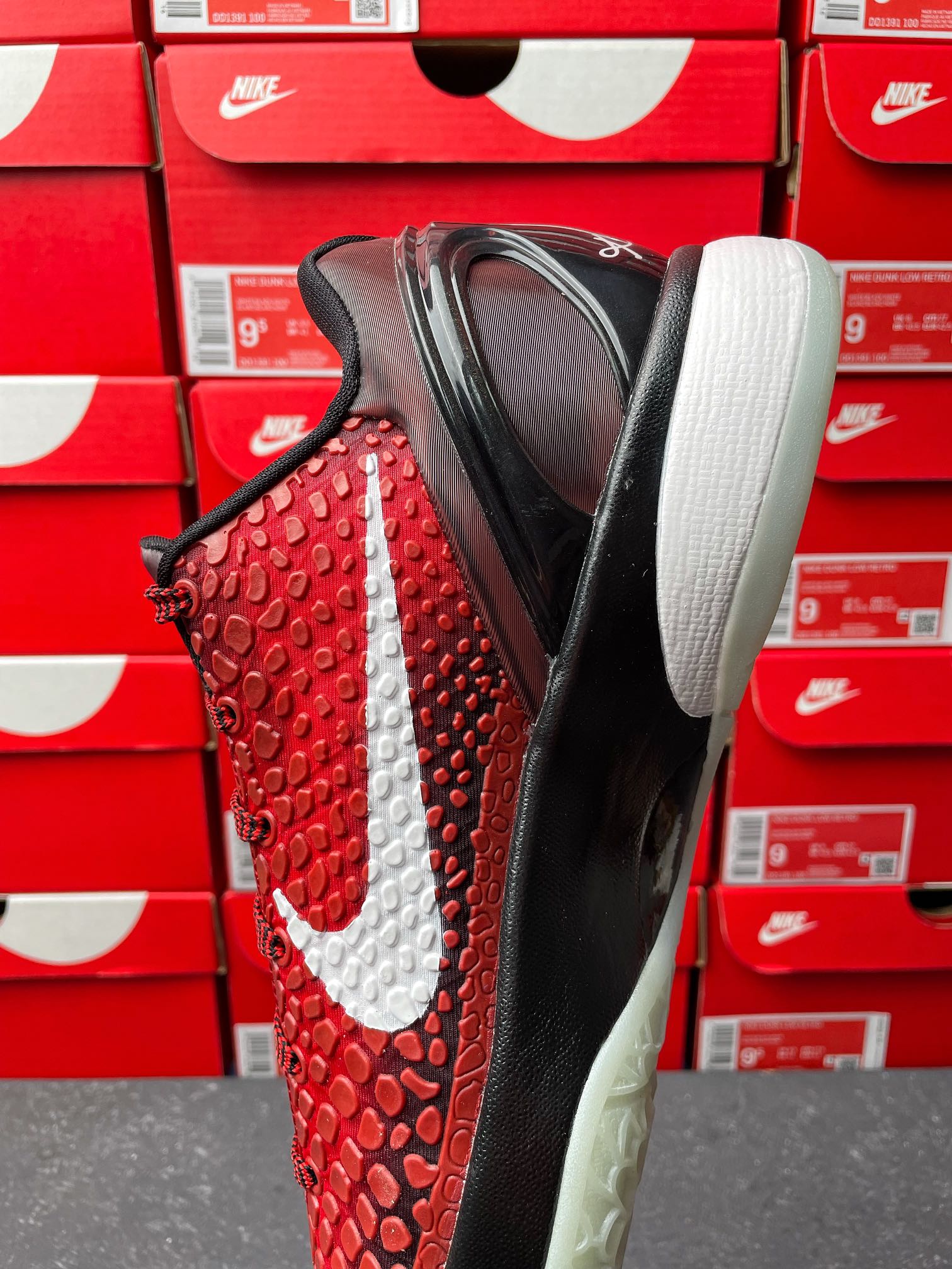 Red athletic shoe with white swoosh, black sole, and rounded white midsole