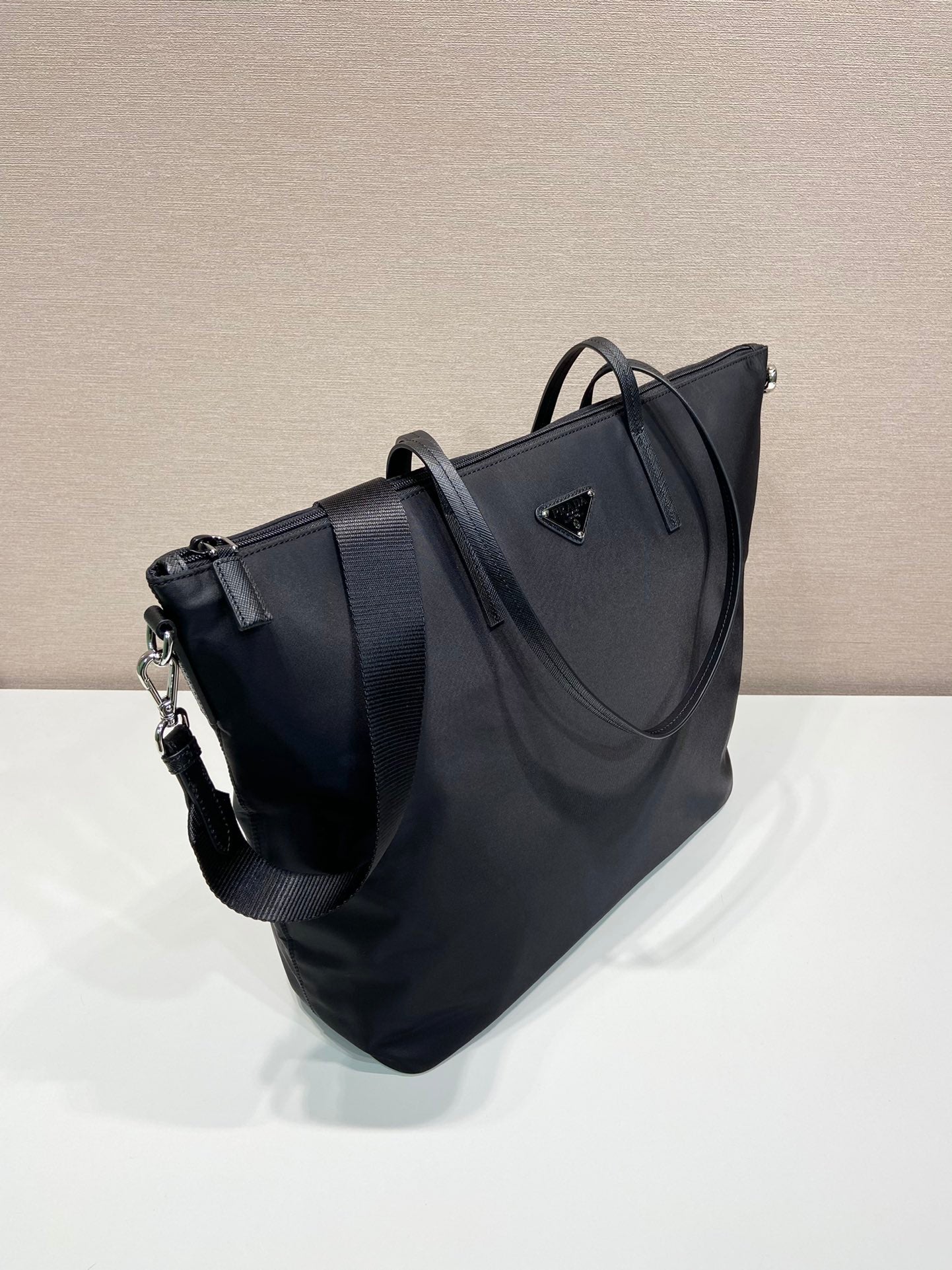 Prada nylon tote bag, angled view, with top handles and adjustable shoulder strap