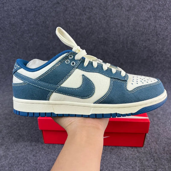 Nike Dunk Low sneakers with blue suede uppers, white swooshes, and lace ties
