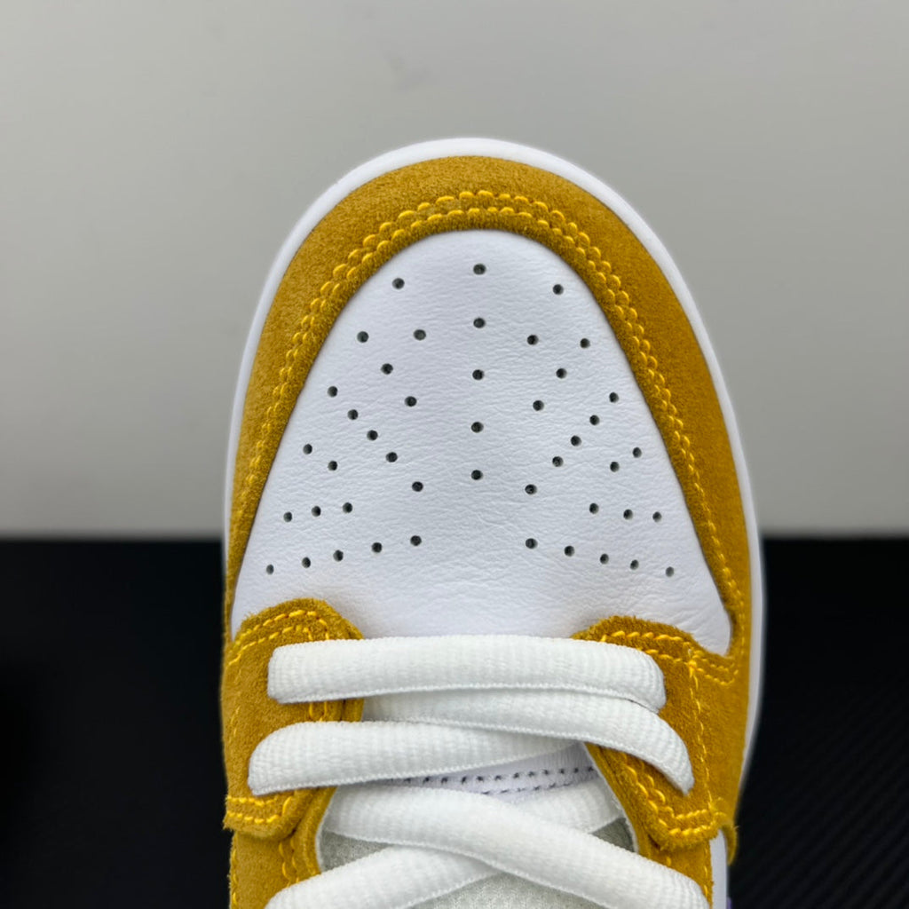 Nike Dunk SB Low Pro toe box close-up in white and gold with perforations and white laces