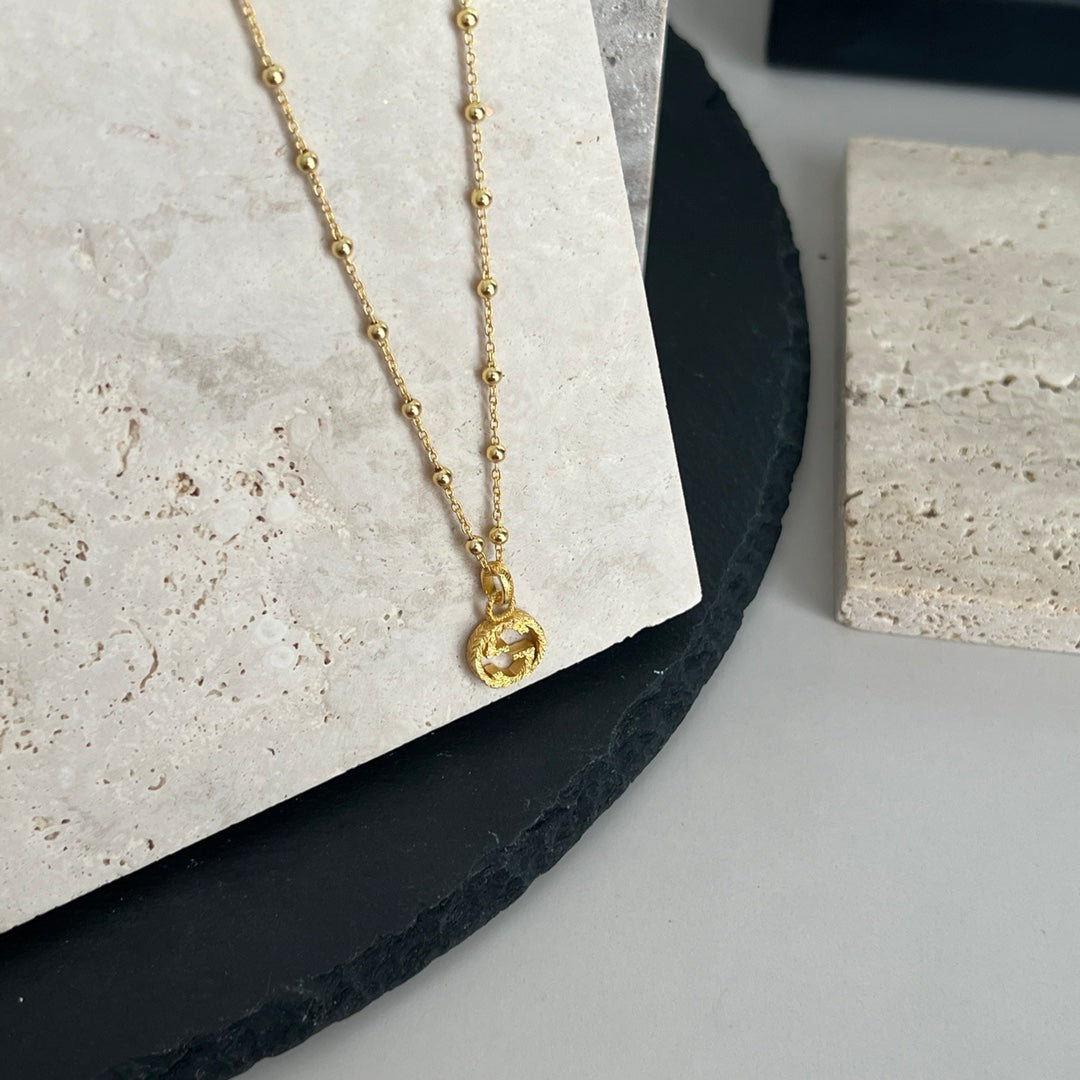 Gucci pendant necklace with gold chain and round logo charm detail