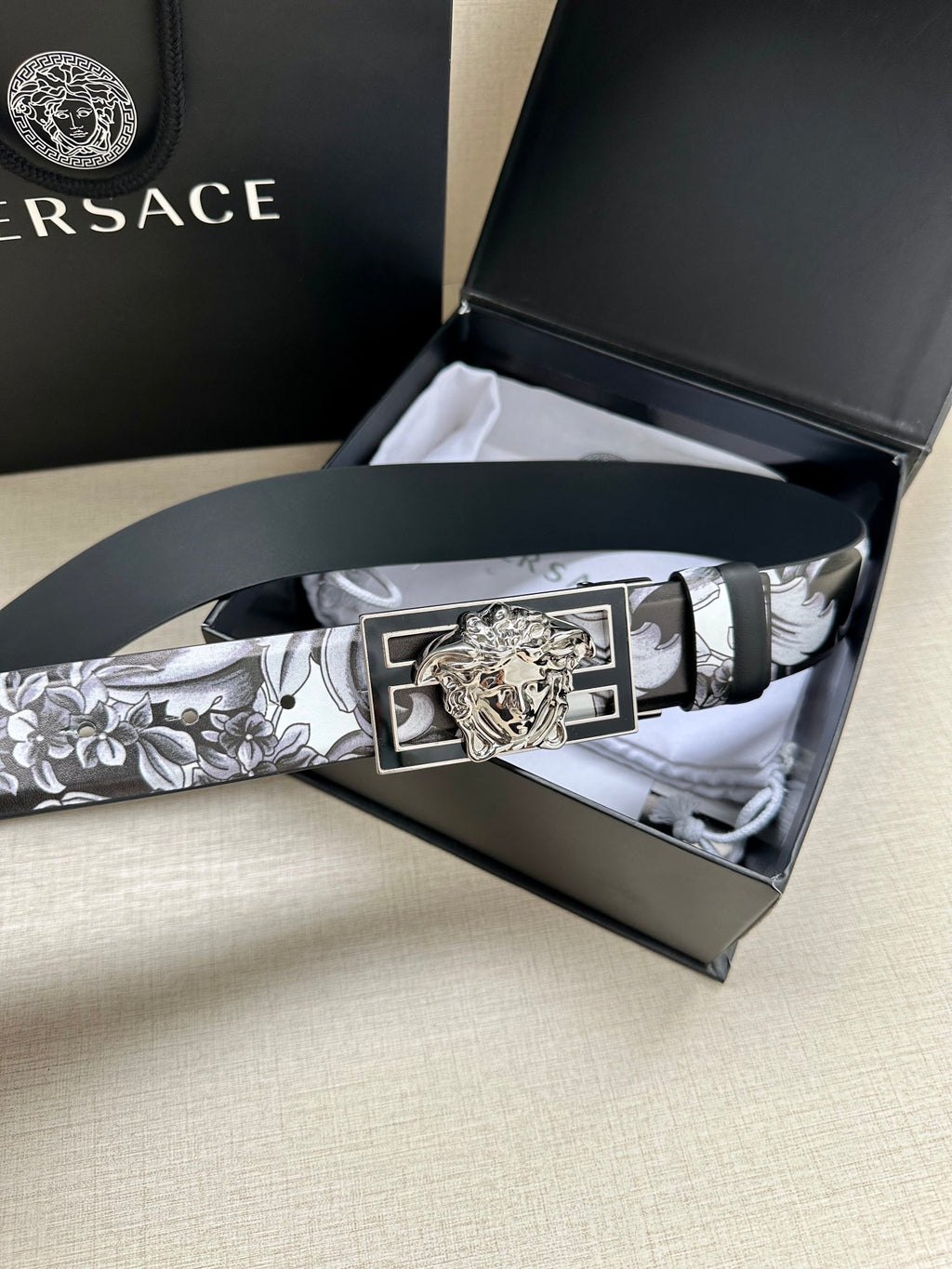 Versace belt in box, black-and-gray patterned strap with silver frame and gold Medusa buckle.