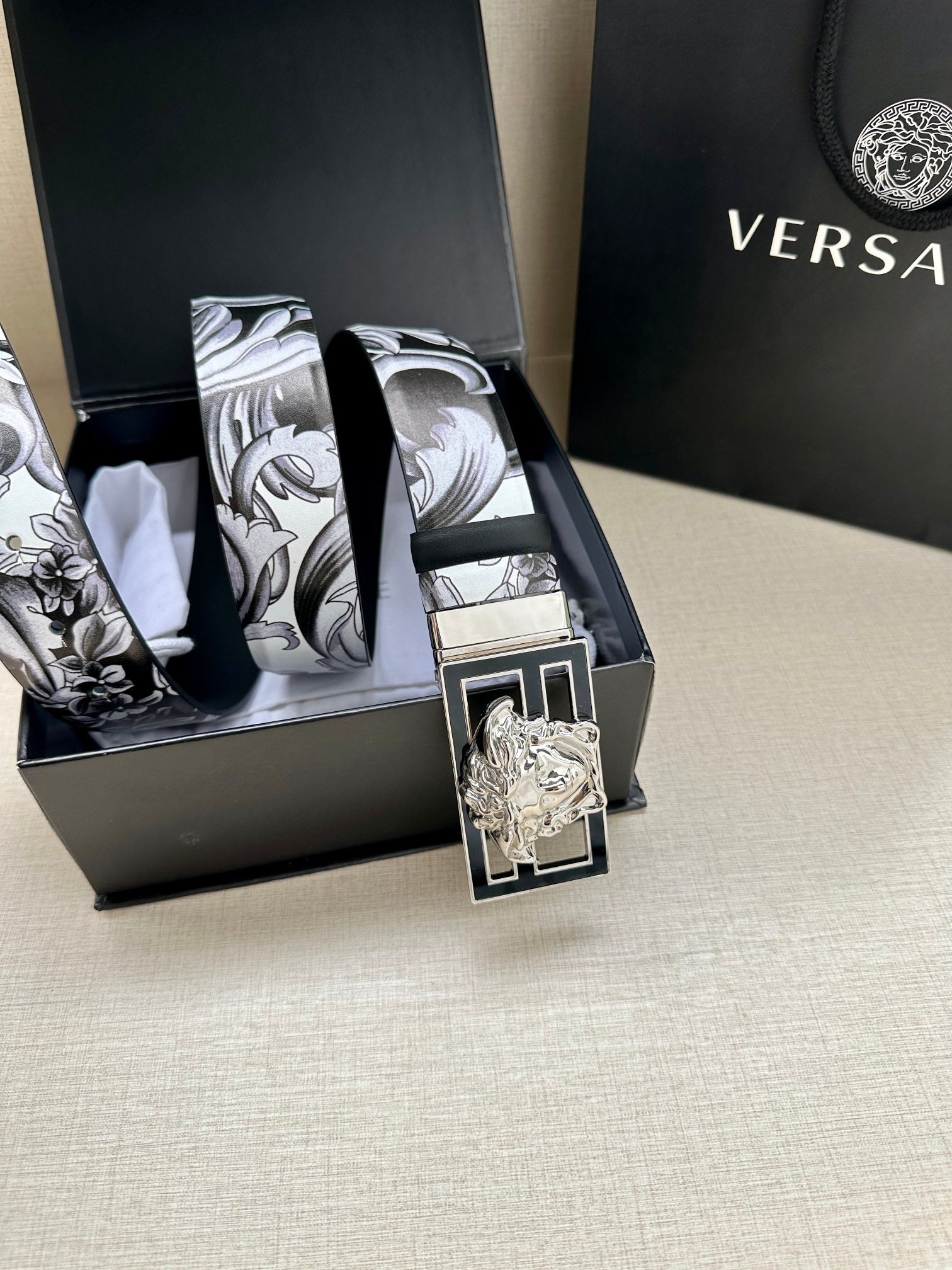 Belt with black-and-gray baroque print strap and silver buckle with Medusa head.