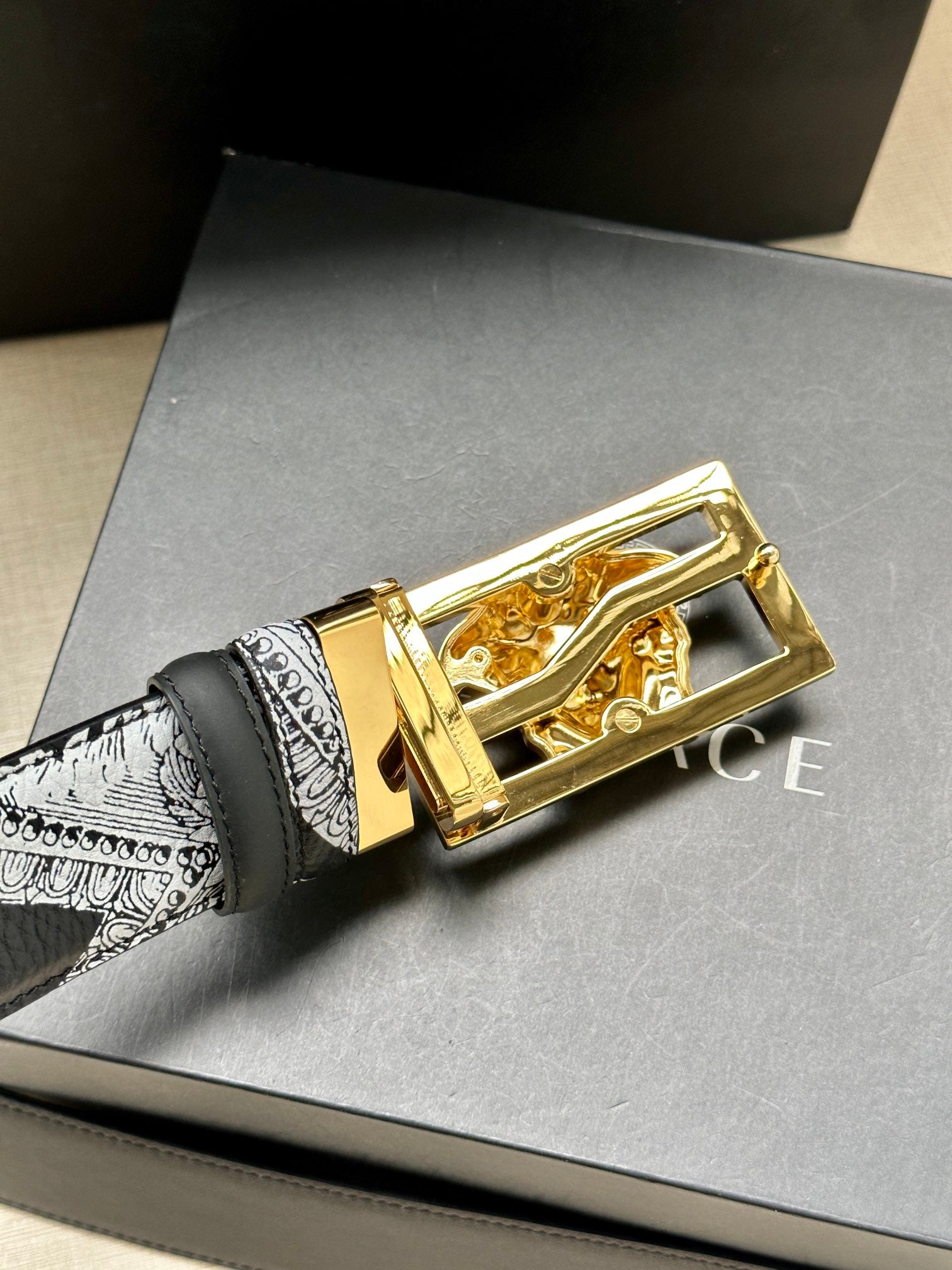 Versace belt buckle close-up with gold-tone finish and Medusa emblem