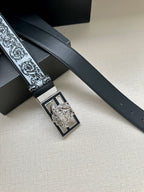 Designer belt detail: dark strap with baroque trim and silver-toned square buckle