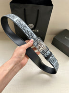 Designer belt on hand: patterned strap with large silver square buckle and Medusa motif