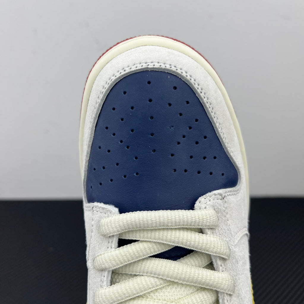 Front view of low-top sneaker showing navy perforated toe and white laces.