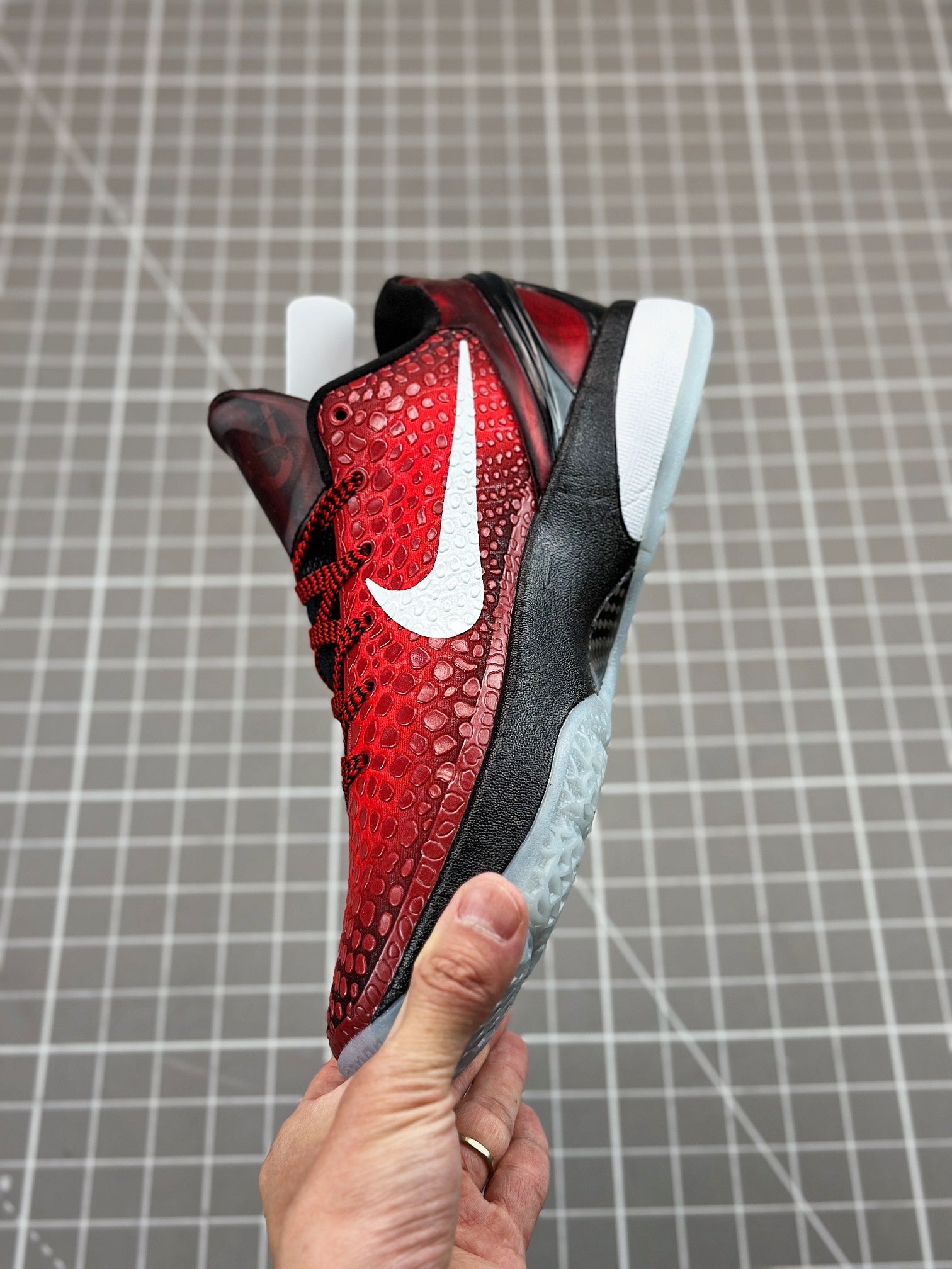 Close rear-side view, red textured upper with white swoosh and black heel cup