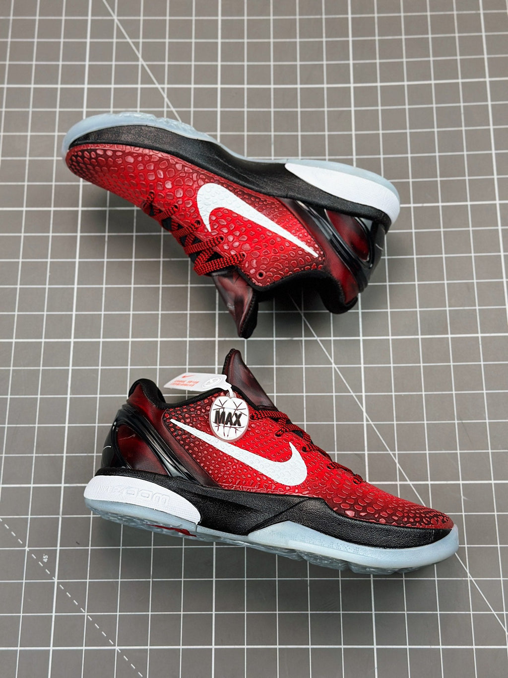 Red and black low-top basketball shoe, outsole and side view with white accents