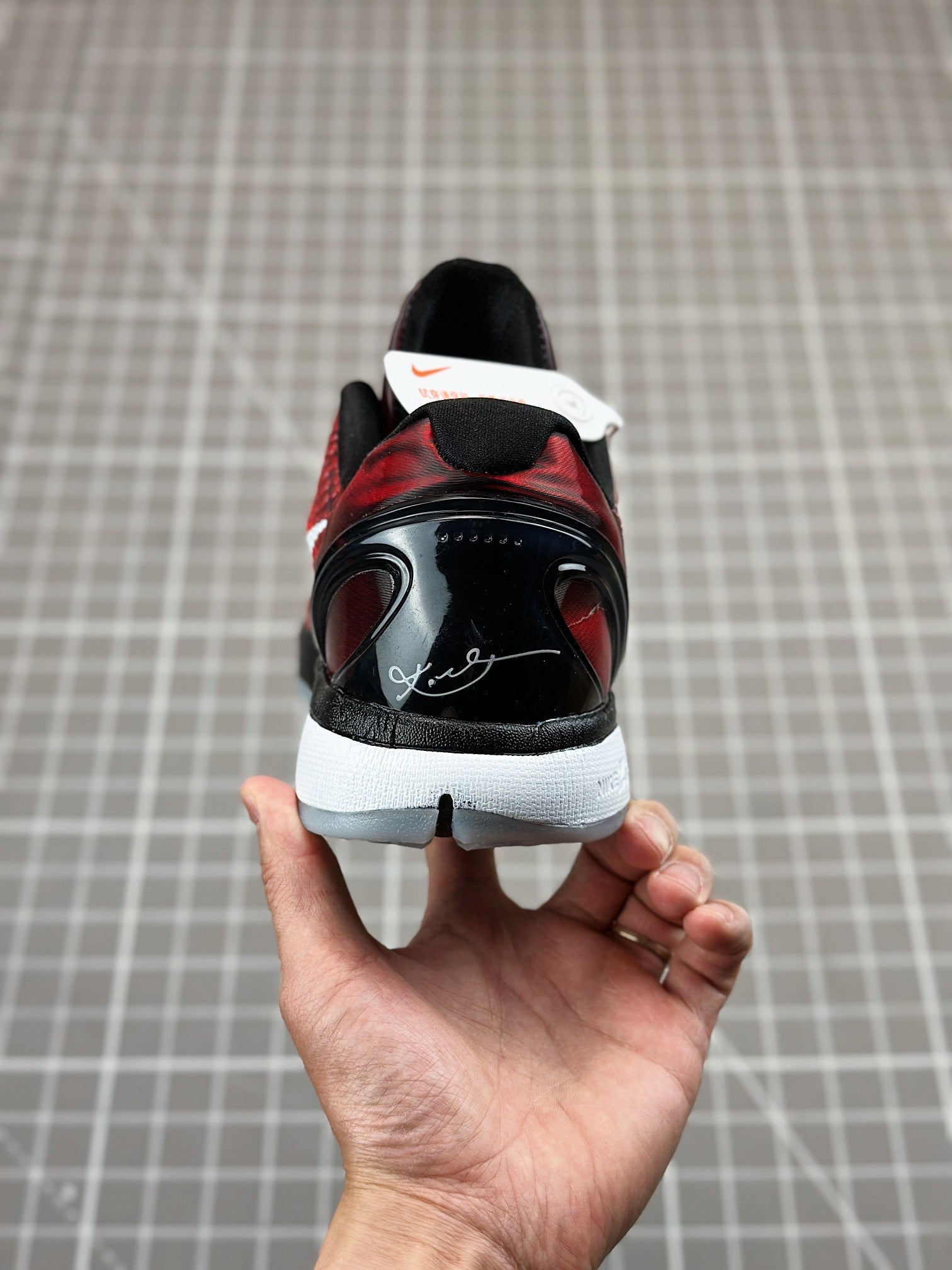 Rear view of red and black basketball shoe, lace-up back heel with white tag