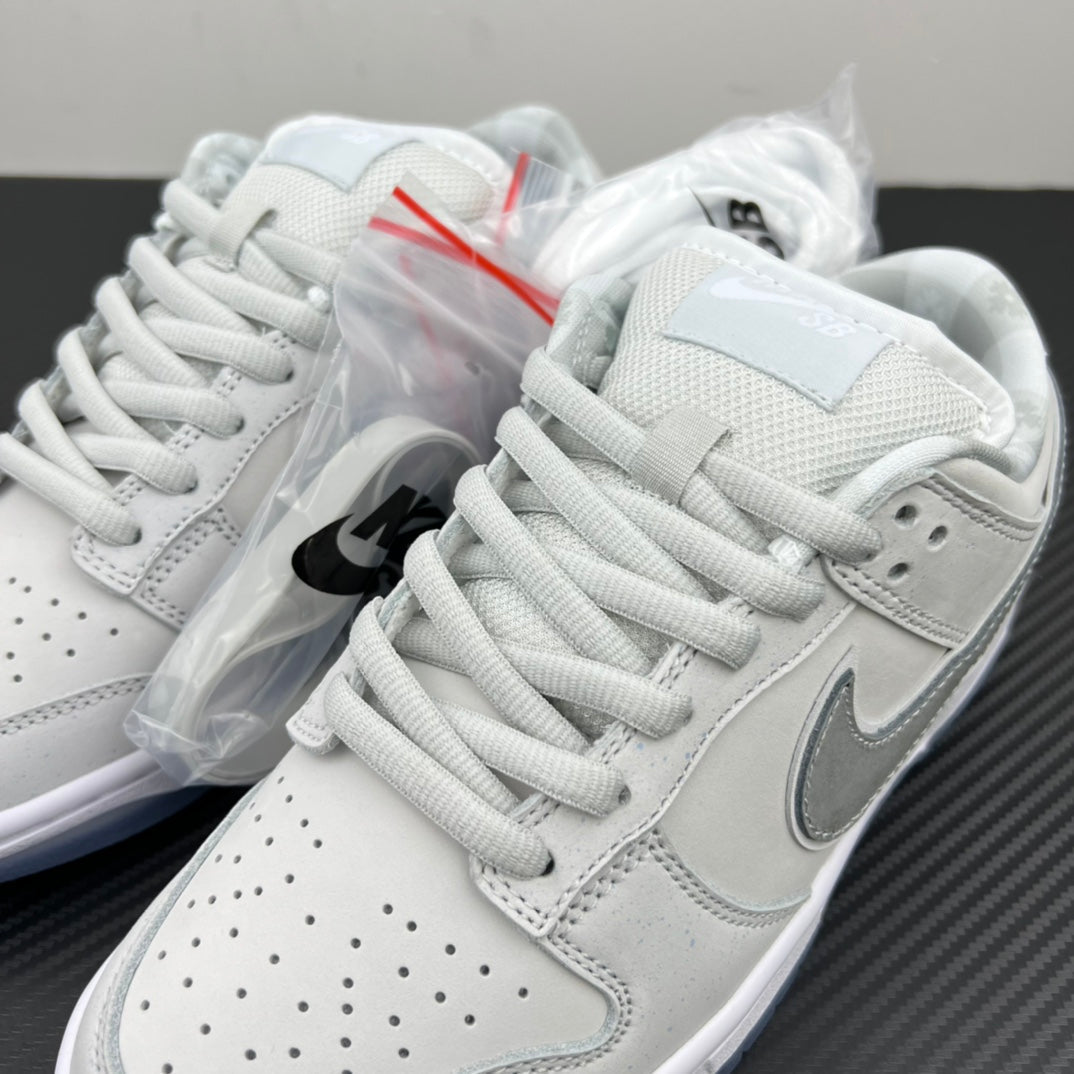 White low-top sneakers with gray swoosh detail and lace-up panels over plastic wrap.