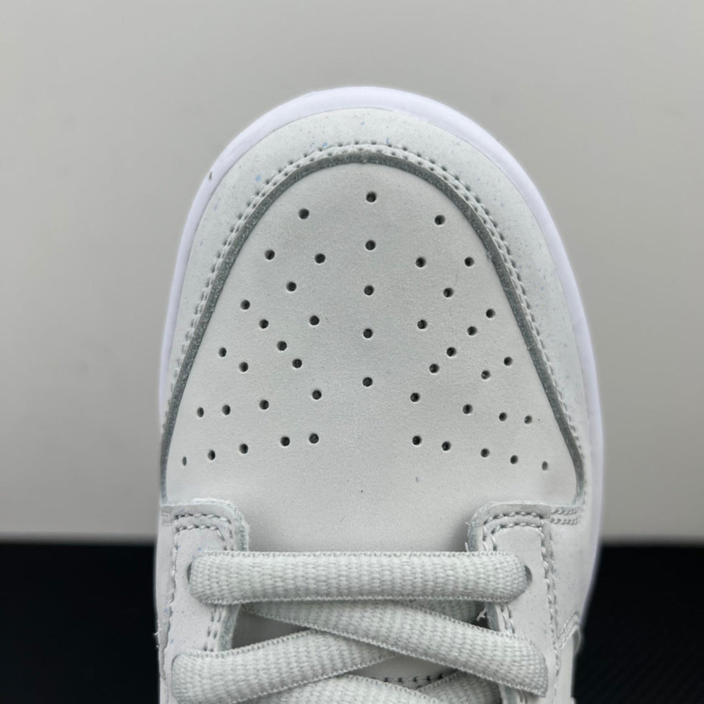 White low-top sneaker toe box close-up with perforations and lace-up front.