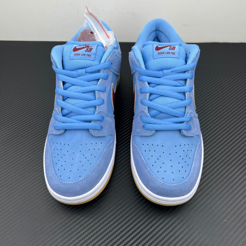 Pair of light blue low-top sneakers with blue laces and maroon tongue branding