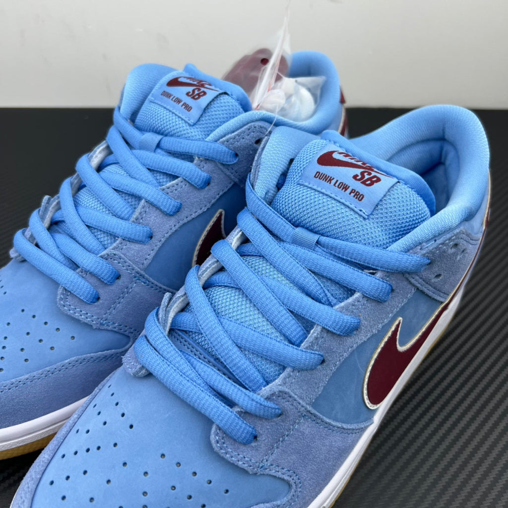 Light blue low-top sneakers with maroon Swoosh and blue laces