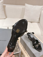 Black leather slide sandal with emblem on footbed and silver buckle strap