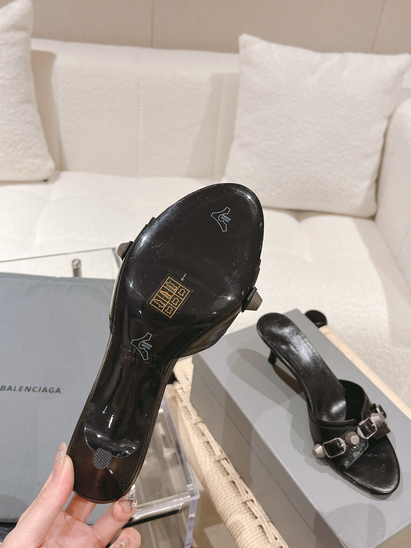 Black leather slide sandal with emblem on footbed and silver buckle strap