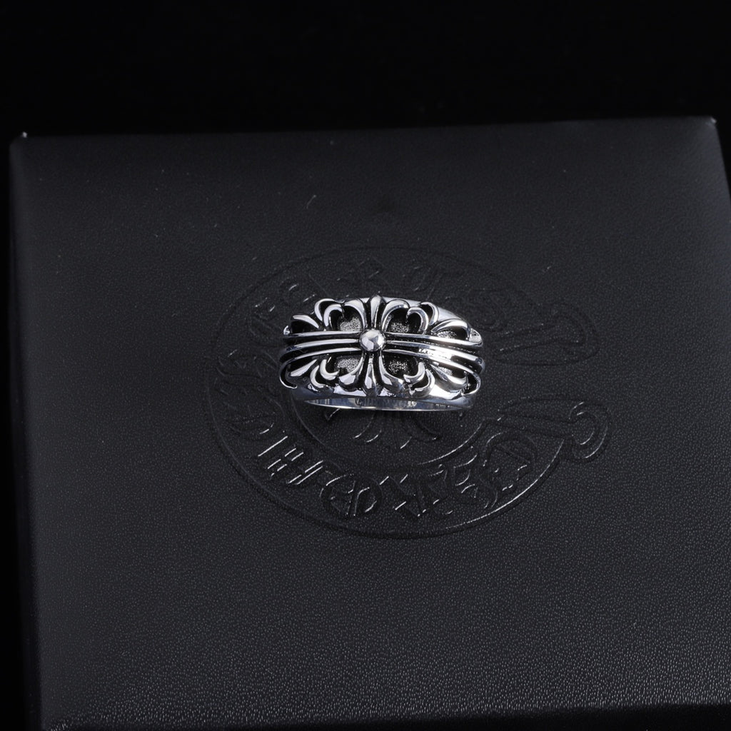 Silver-tone ornate chrome ring with central round gemstone and braided-looking band.