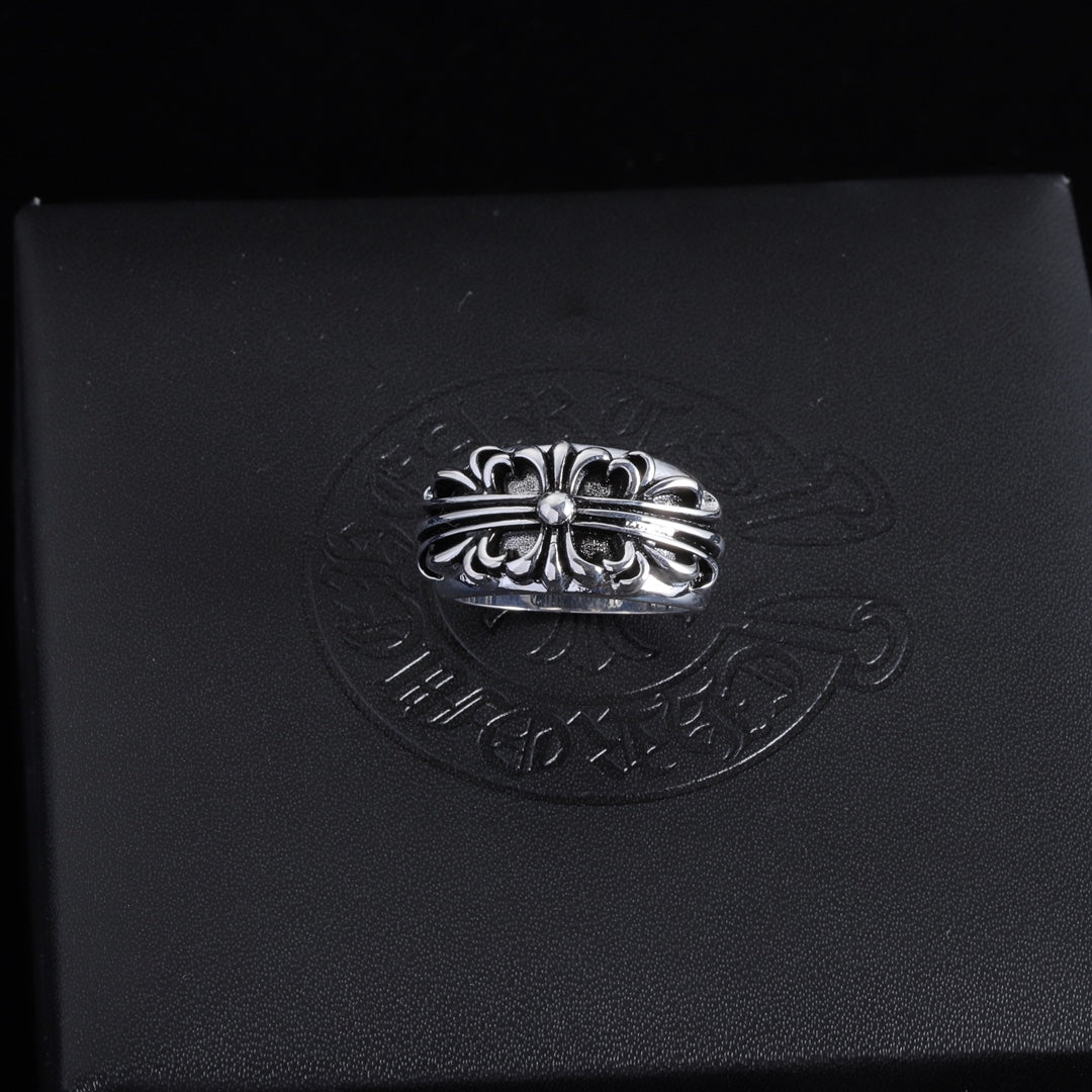 Silver-tone ornate chrome ring with central round gemstone and braided-looking band.