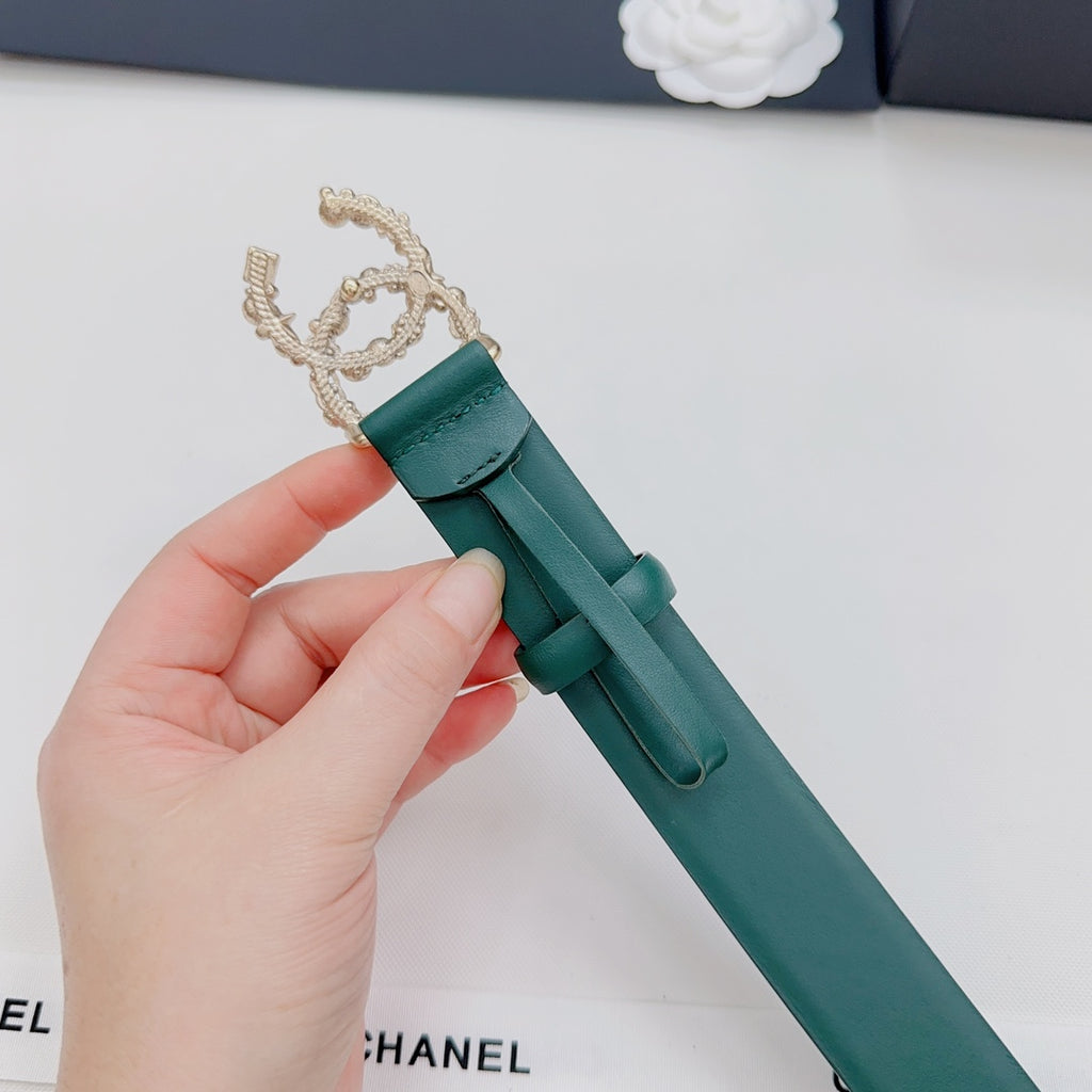 Green Chanel belt with gold chain-like buckle and pearl detail, held by hand