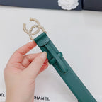 Green Chanel belt with gold chain-like buckle and pearl detail, held by hand