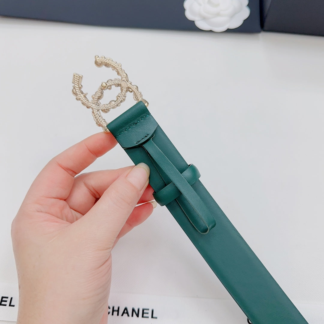 Green Chanel belt with gold chain-like buckle and pearl detail, held by hand