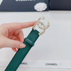Green Chanel belt end with gold and pearl buckle decoration, held in hand