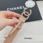 Beige Chanel belt with gold-tone jeweled buckle detail, hand holding strap
