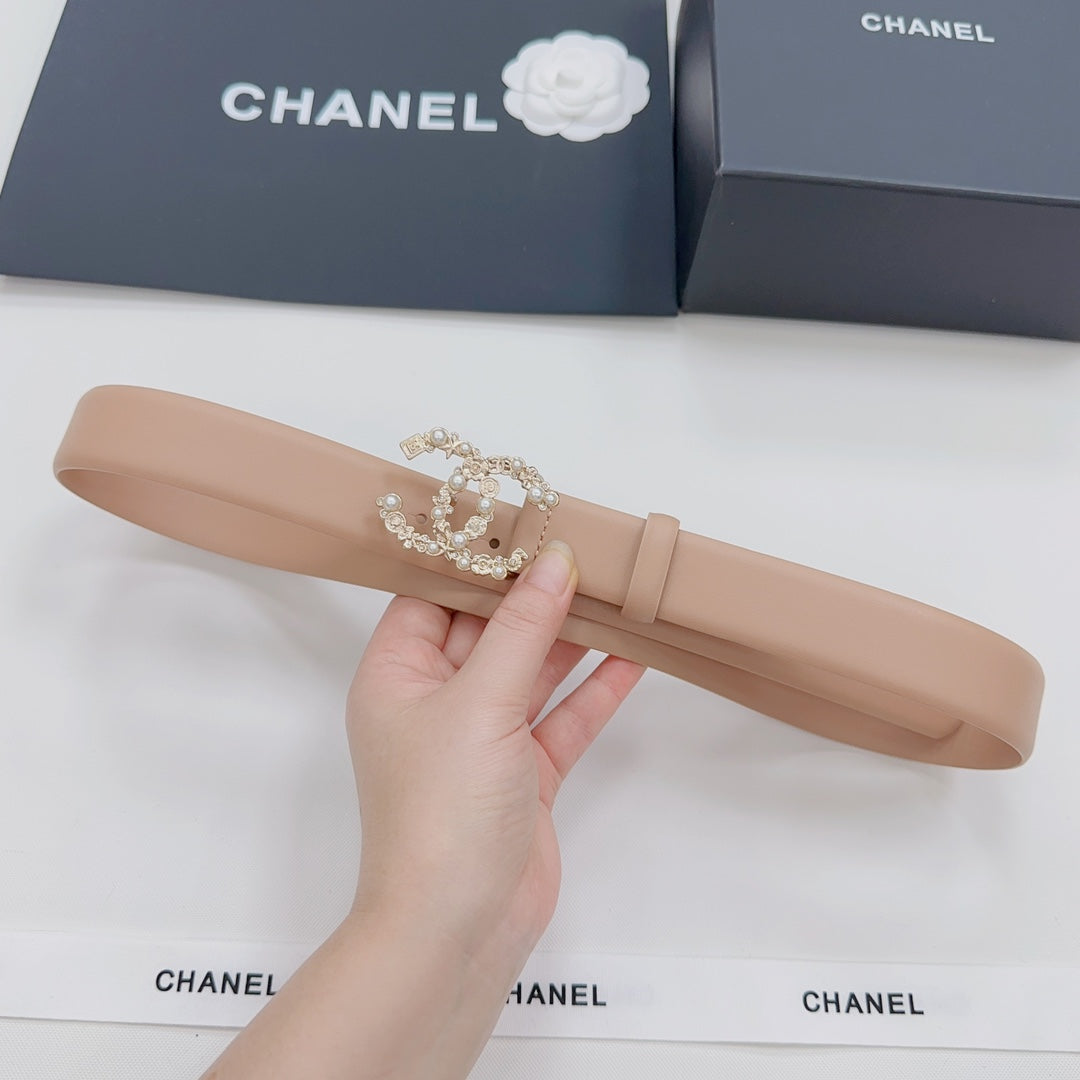 Beige Chanel belt with embellished logo buckle, held in hand