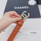 Orange belt with rhinestone-style silver CC buckle, held for close view.