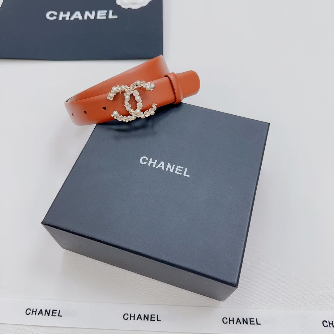 Orange belt with silver-tone ornate buckle detail, laid across a box.